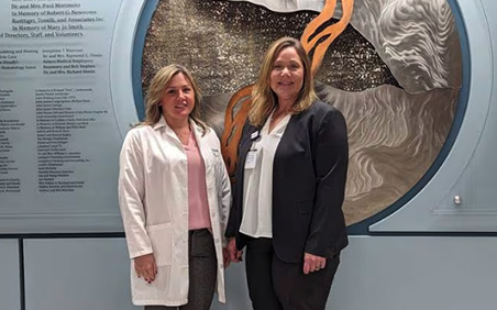 Nicole Hartley, lead nurse practitioner for Lightways’ serious illness care program (left) and Lisa Heiy, director of Lightways’ serious illness care (right) pose in front of the donor wall on Monday, March 4, 2024, at Lightways in Joliet. (Denise Unland)