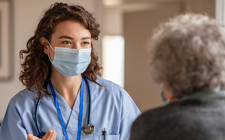 Nurse with Mask talking to elderly patient