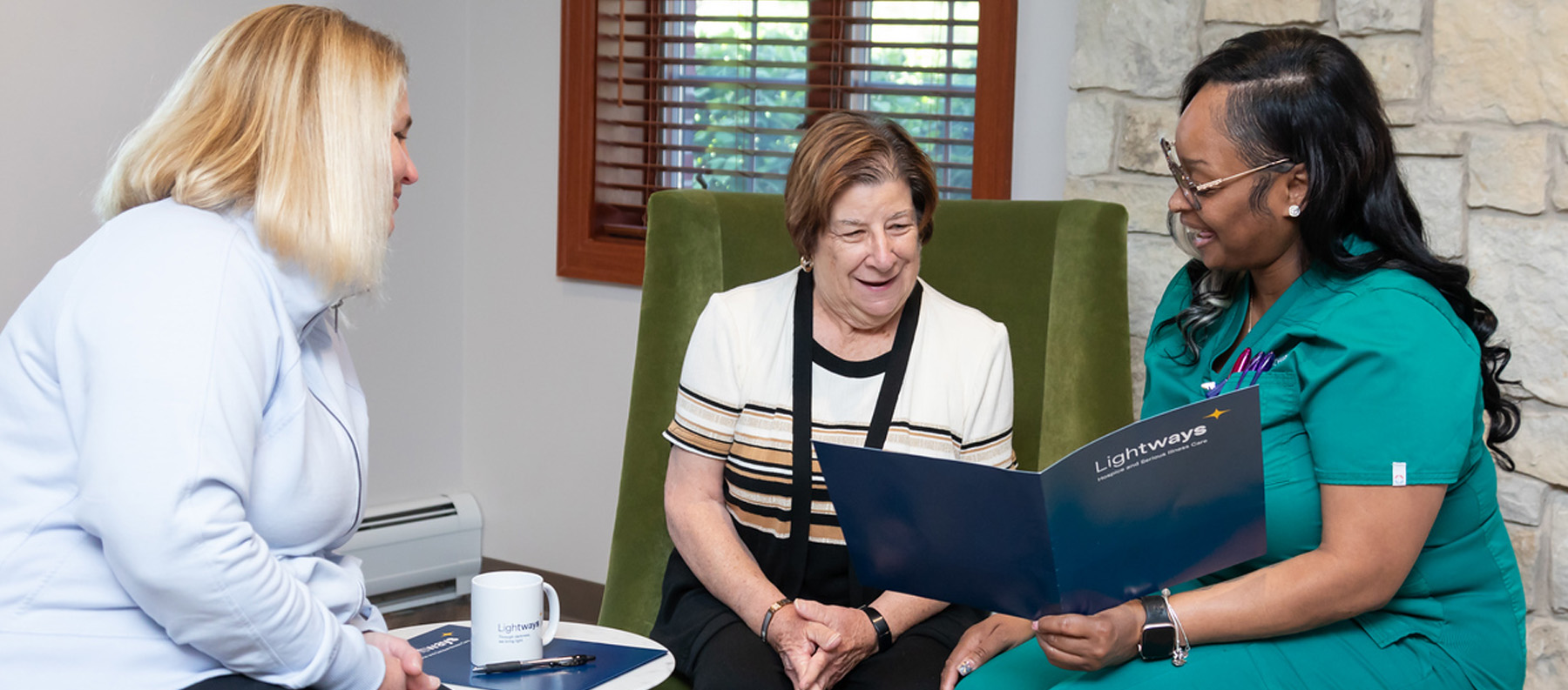 Lightways staff reviewing folder of advanced directive services with mother and daughter.