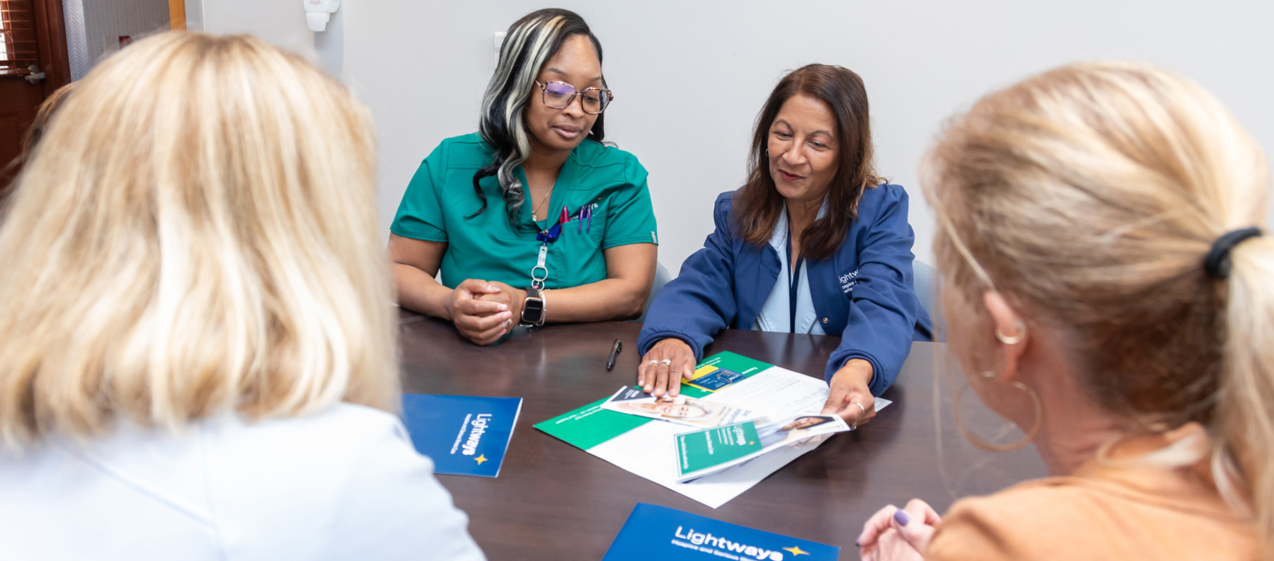 Lightways Joliet nurses sitting at a table reviewing patient care materials with a mom and daughter