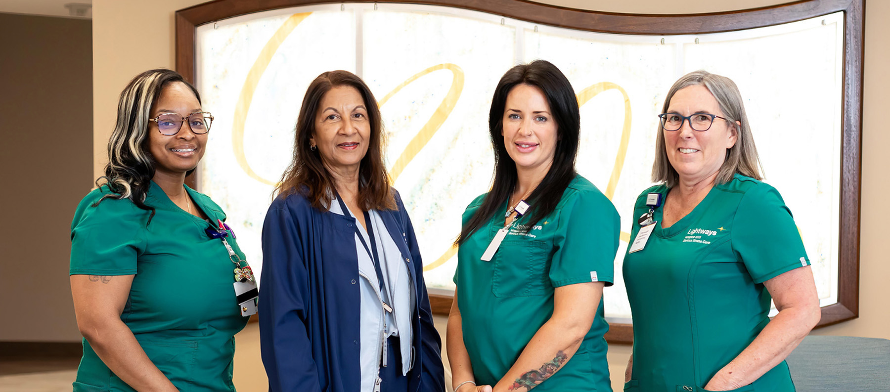 Serious Illness Care nurses standing in front of donor wall at Lightways Joliet.